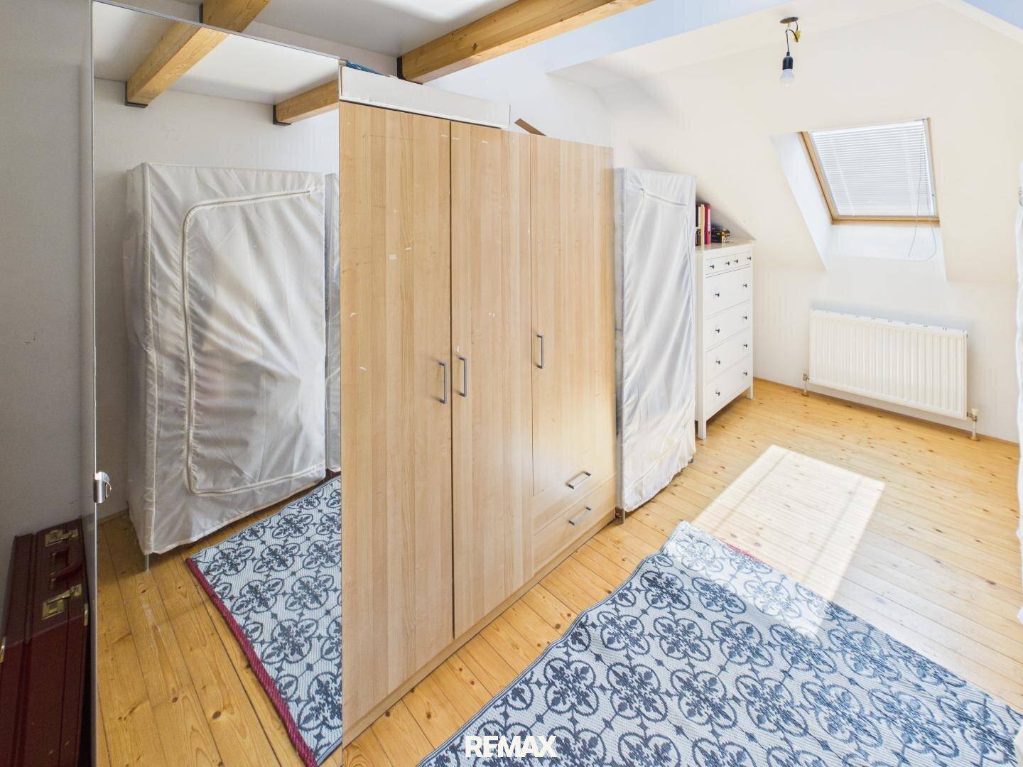 Schlafzimmer mit Holzboden, Kleiderschrank, Dachschräge und Dachfenster.
