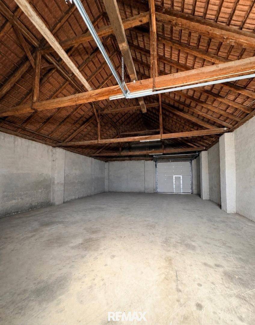 Geräumige Garage mit Betonboden und sichtbarer Holzkonstruktion des Dachstuhls, bereit zur Nutzung.