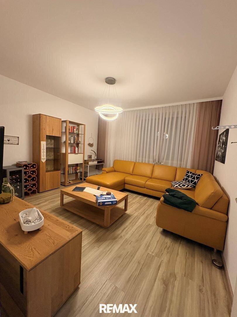 Gemütliches Wohnzimmer mit gelbem Ecksofa, Holztisch und Laminatboden, ideal für entspannte Abende.