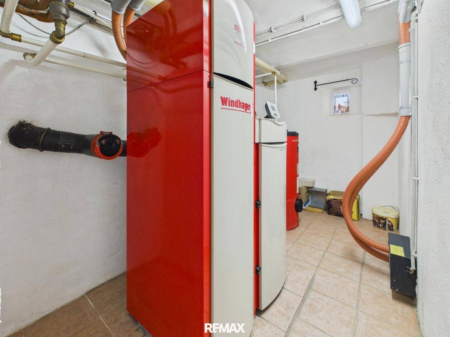 Heizungsraum im Keller mit einem modernen Pelletkessel und sichtbaren Rohrleitungen.