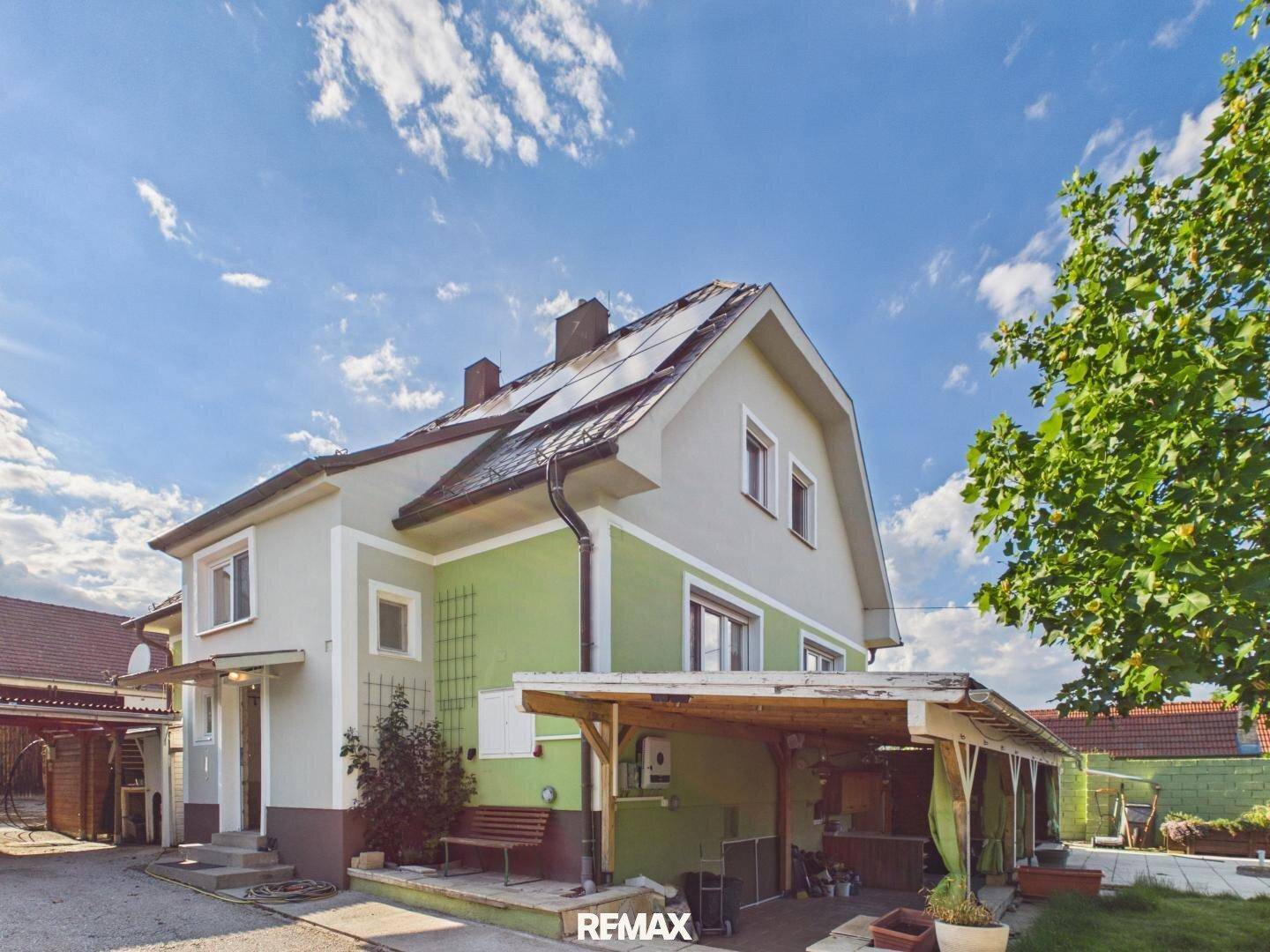 Seitenansicht des Hauses mit Solarpaneelen auf dem Dach und einem überdachten Eingangsbereich.