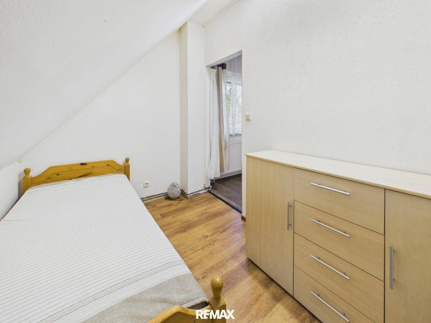 Gemütliches Schlafzimmer im Dachgeschoss mit Einzelbett, Laminatboden und schrägen Wänden.