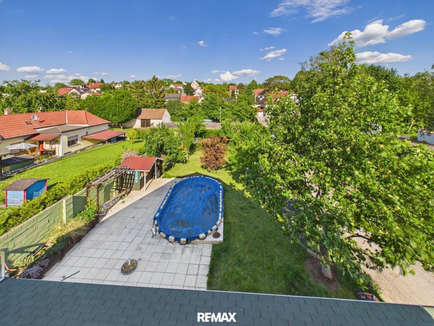 Luftaufnahme des Gartens mit einem Pool, Rasenflächen und umliegenden Häusern in der Nachbarschaft.