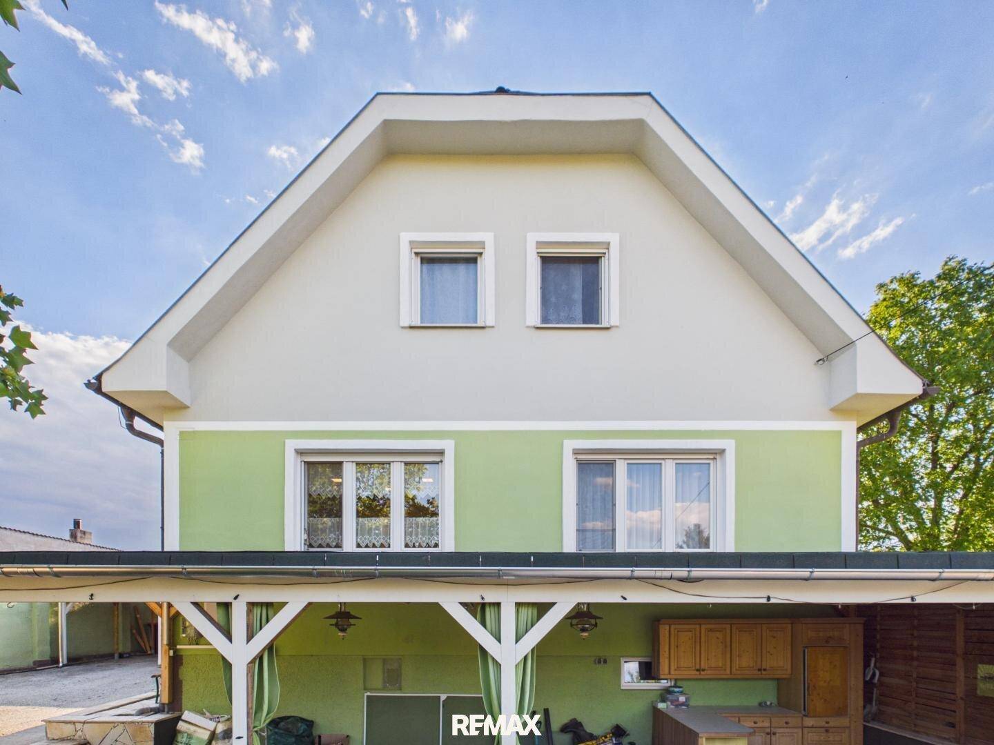 Rückansicht des Hauses mit Giebeldach und einem überdachten Bereich, der als Außenküche dient.