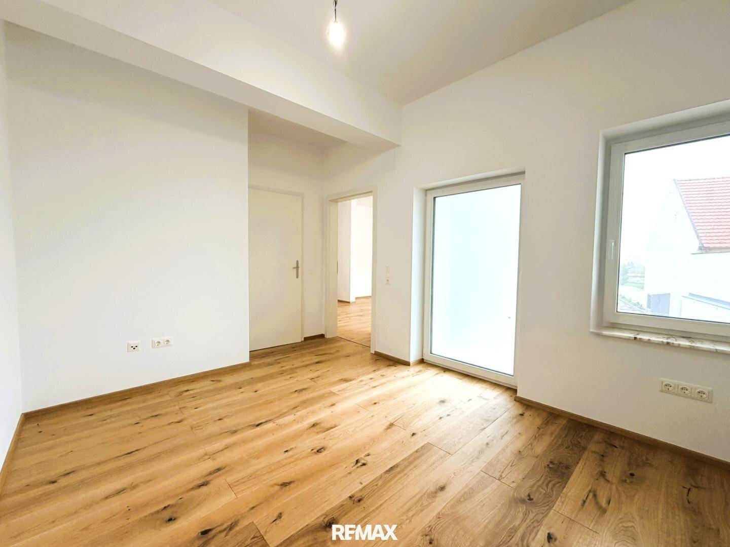 Heller, unmöblierter Raum mit Holzboden und Fenster, das viel Tageslicht in den Raum bringt.
