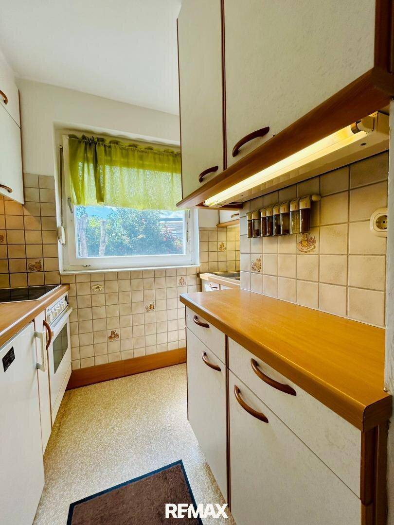 Funktionale Küche im traditionellen Stil mit Holz-Arbeitsplatten und Fensterblick ins Grüne.