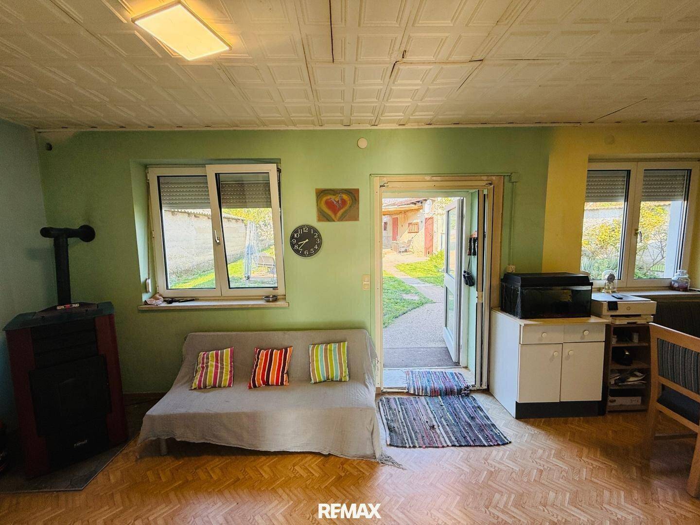 Helles Wohnzimmer mit Kaminofen, Sofa und direktem Zugang zum Garten, gemütlich eingerichtet.