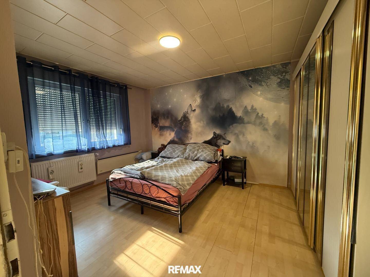 Schlafzimmer mit großem Wandbild, Doppelbett und Spiegelschränken, gut beleuchtet durch ein Fenster.