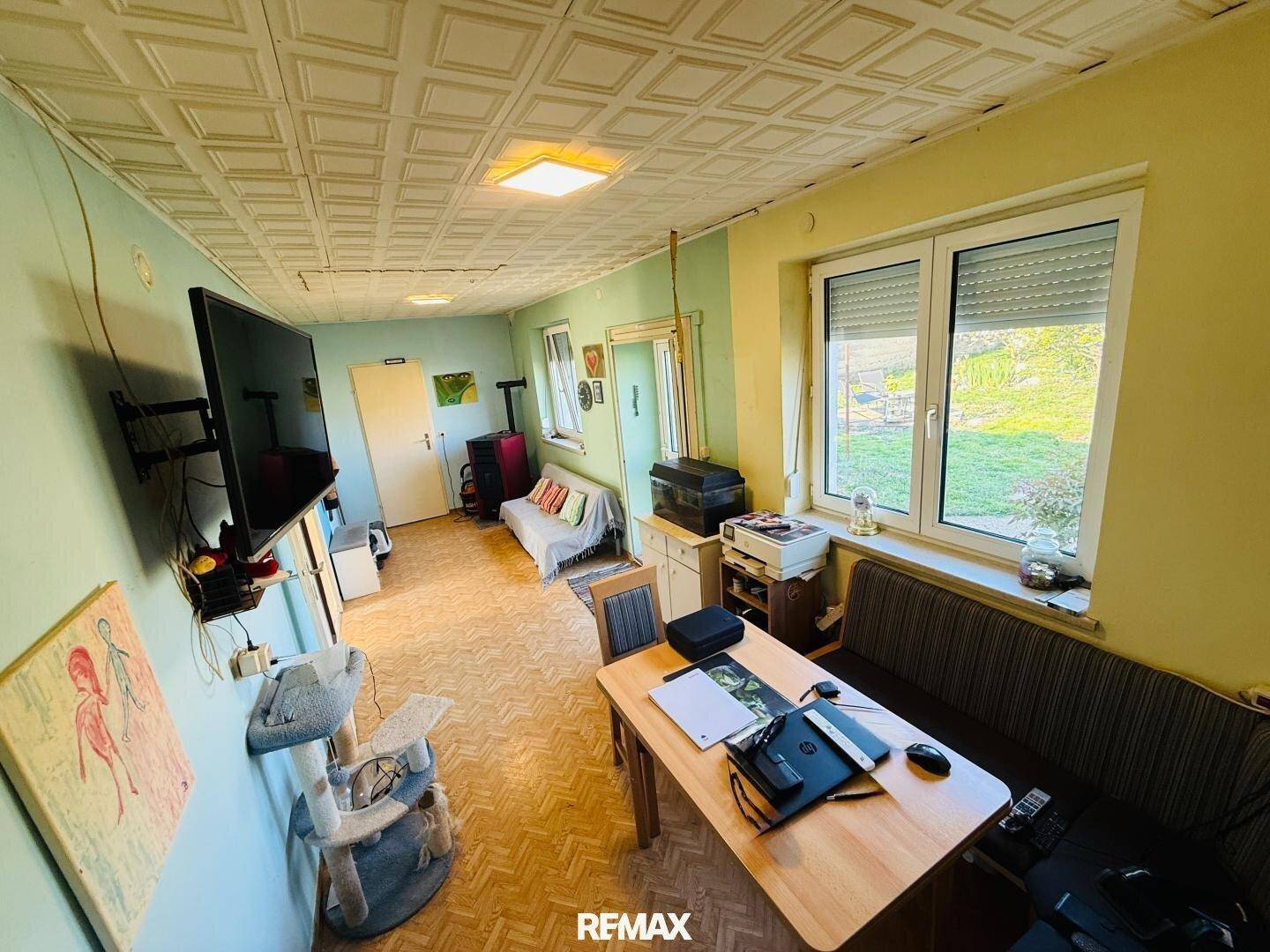 Geräumiges Wohnzimmer mit Esstisch, Sofa und Fernseher, hell und mit Blick ins Grüne.