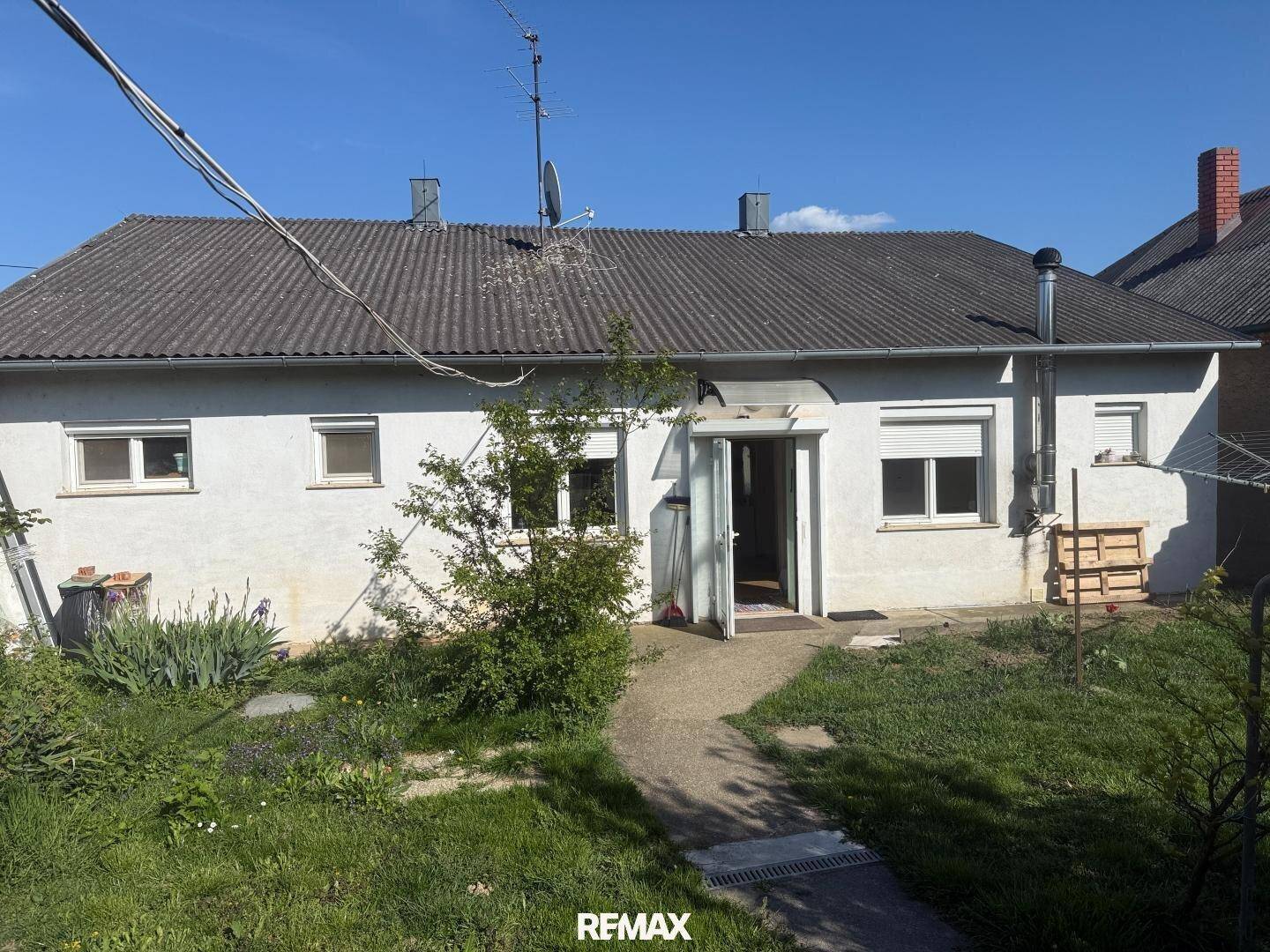Rückseite des Hauses mit weißer Fassade, Rollläden und Zugang zum Gartenbereich.