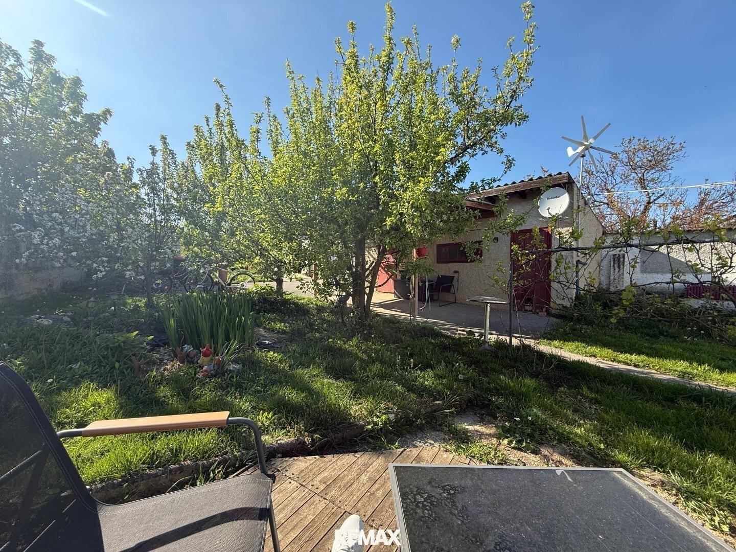 Grüner Garten mit Bäumen und einem kleinen Nebengebäude im Hintergrund, ideal zum Entspannen.