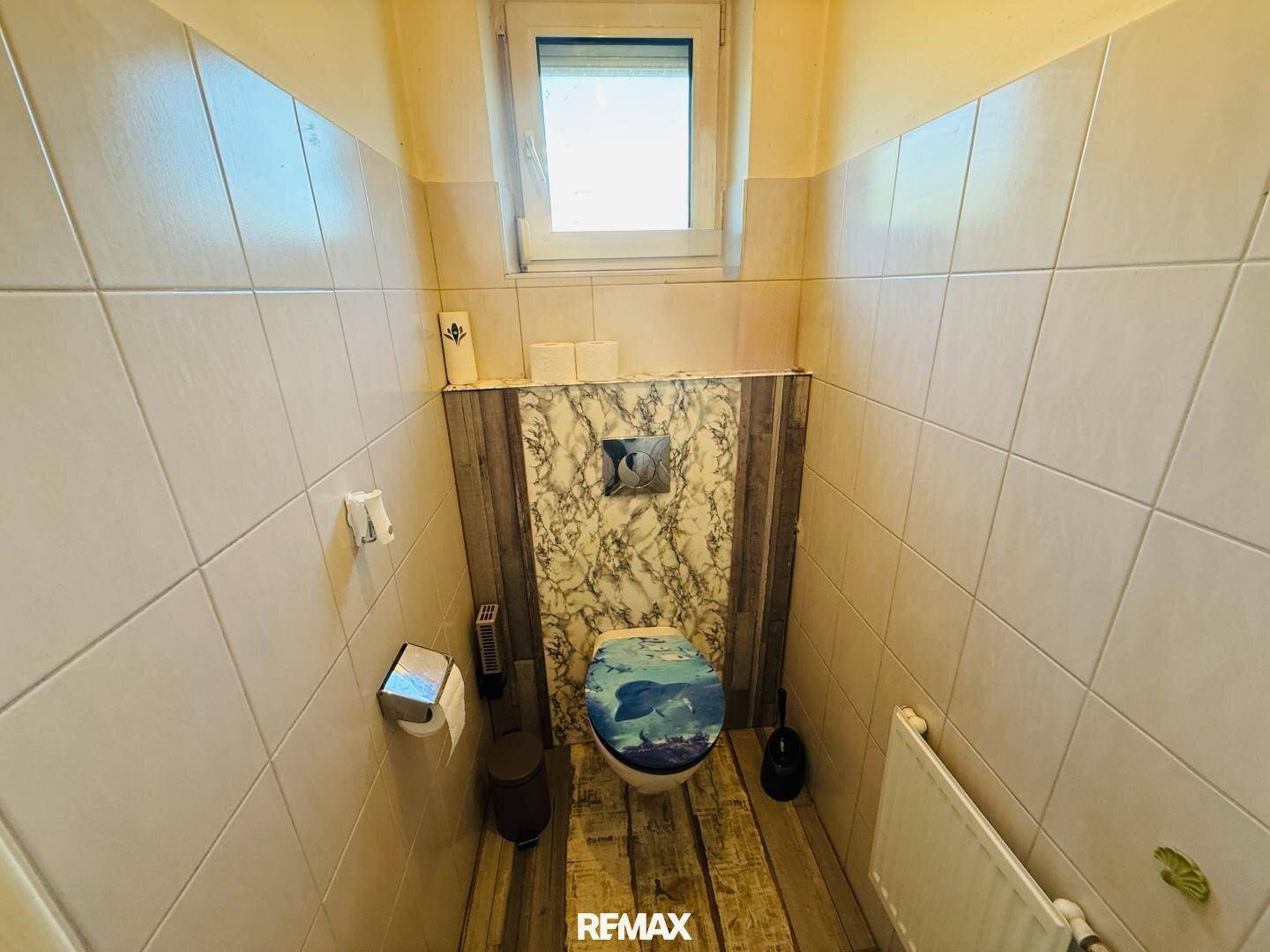 Separate Toilette mit Fenster und Wand-WC, einfach und sauber gefliest.