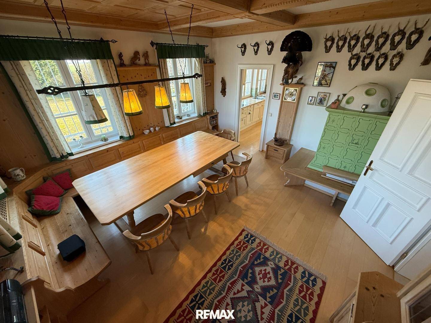 Gemütliches Esszimmer im alpinen Stil mit Holztäfelung, großem Holztisch und Kachelofen.