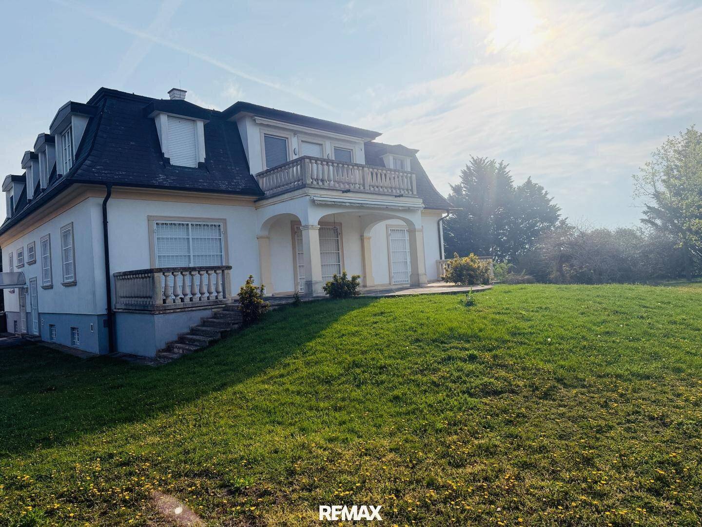Elegante Villa mit weitläufiger Rasenfläche und sonniger Ausrichtung, umgeben von grüner Natur.