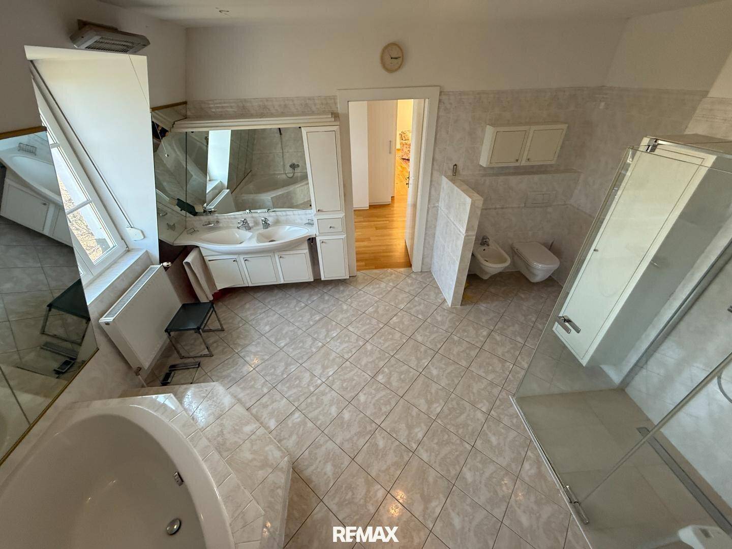 Geräumiges Badezimmer mit Eckbadewanne, Doppelwaschbecken, Bidet und Duschkabine.