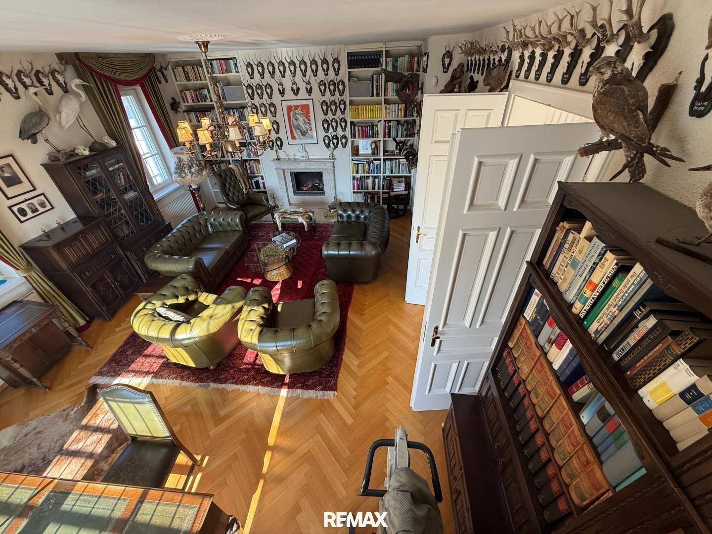 Exklusive Bibliothek mit raumhohen Bücherregalen, Ledersofas und Jagdtrophäen an den Wänden.