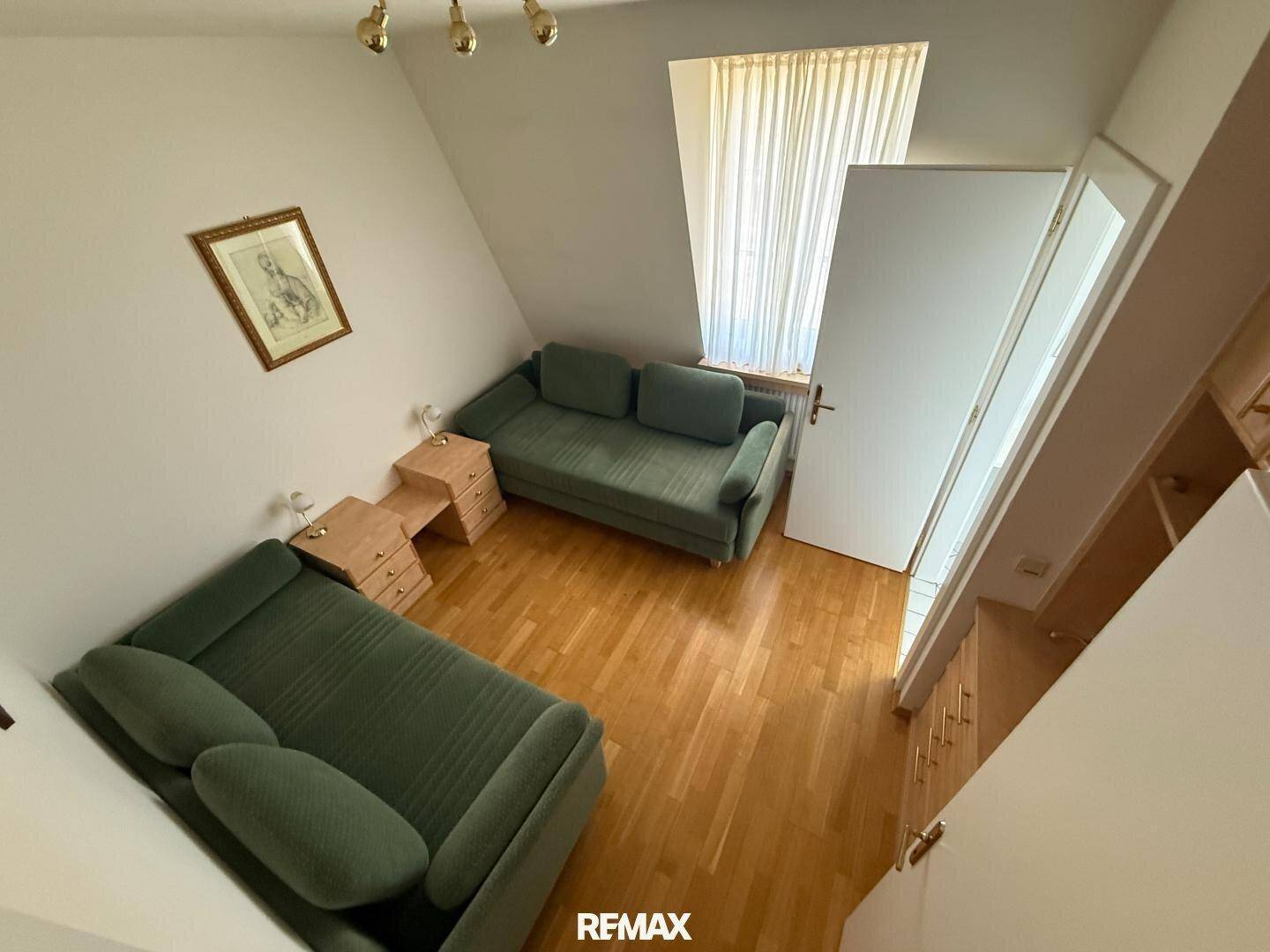 Gemütliches Schlafzimmer im Dachgeschoss mit zwei Einzelbetten, Holzboden und Dachfenster.