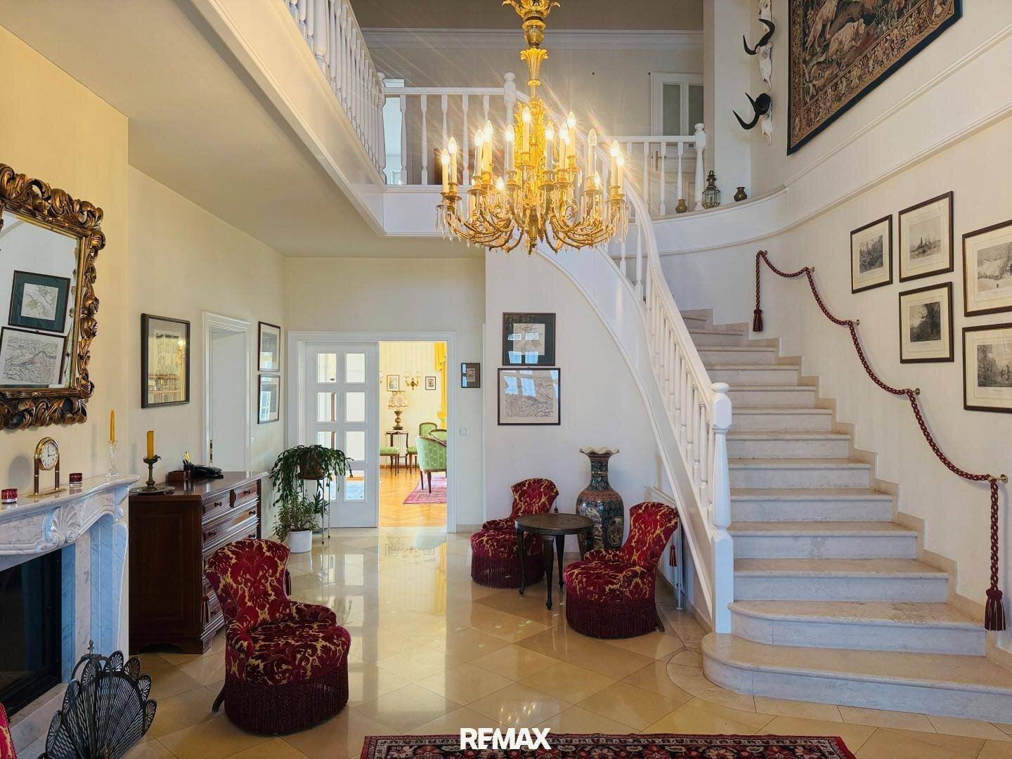 Elegante Eingangshalle mit geschwungener Treppe, Kronleuchter und klassischer Dekoration.