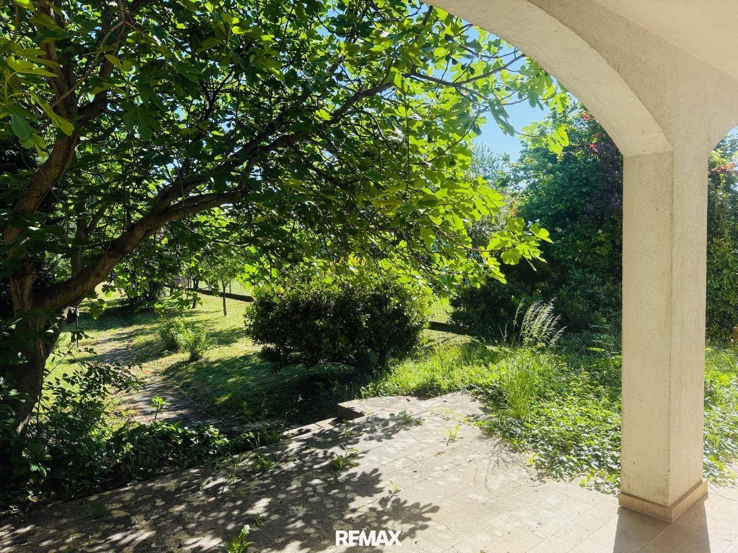 Gemütliche überdachte Terrasse mit viel Grün und schattigen Plätzen im Garten.