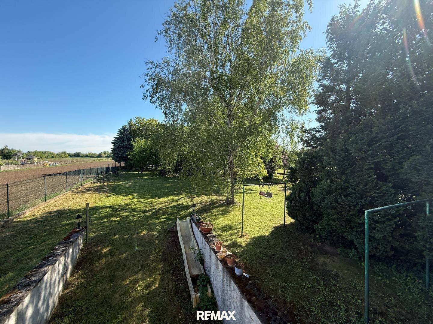 Weitläufiger Garten mit Schaukel und Blick auf die umliegende, grüne Landschaft.