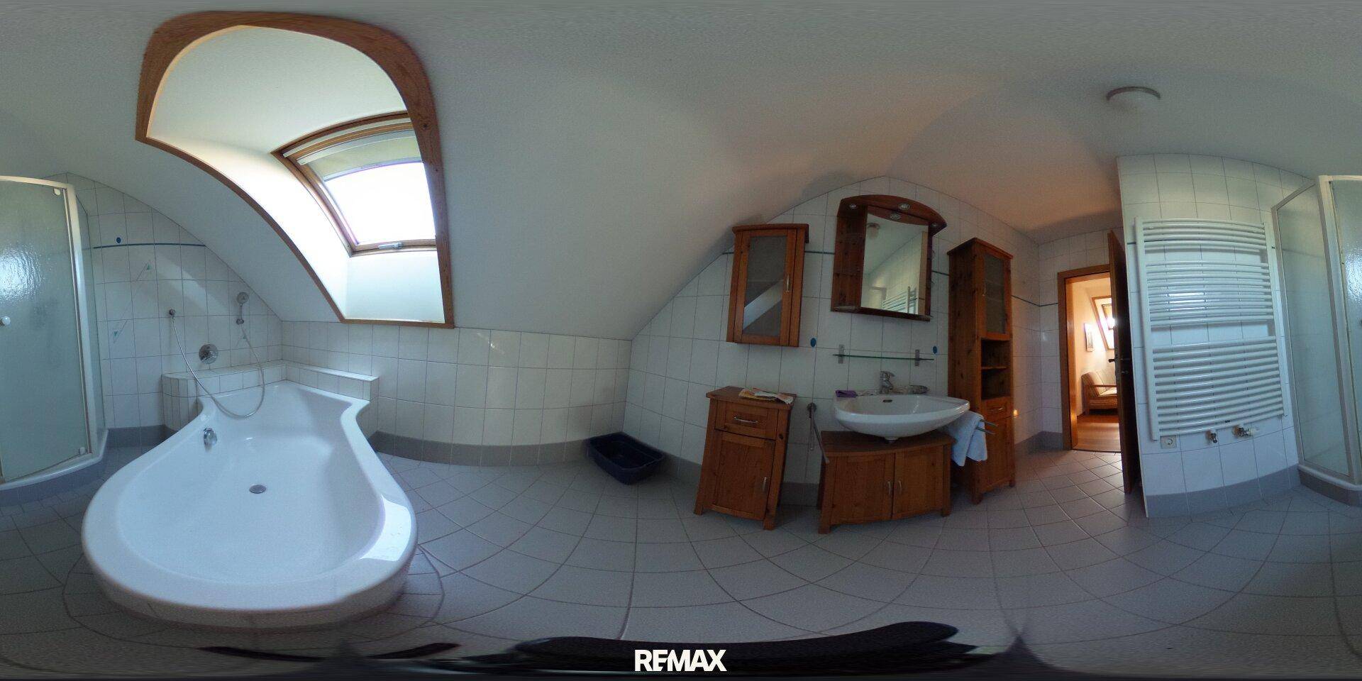 Helles Dachgeschoss-Badezimmer mit Badewanne, Dusche, Holzmöbeln und einem Dachfenster.