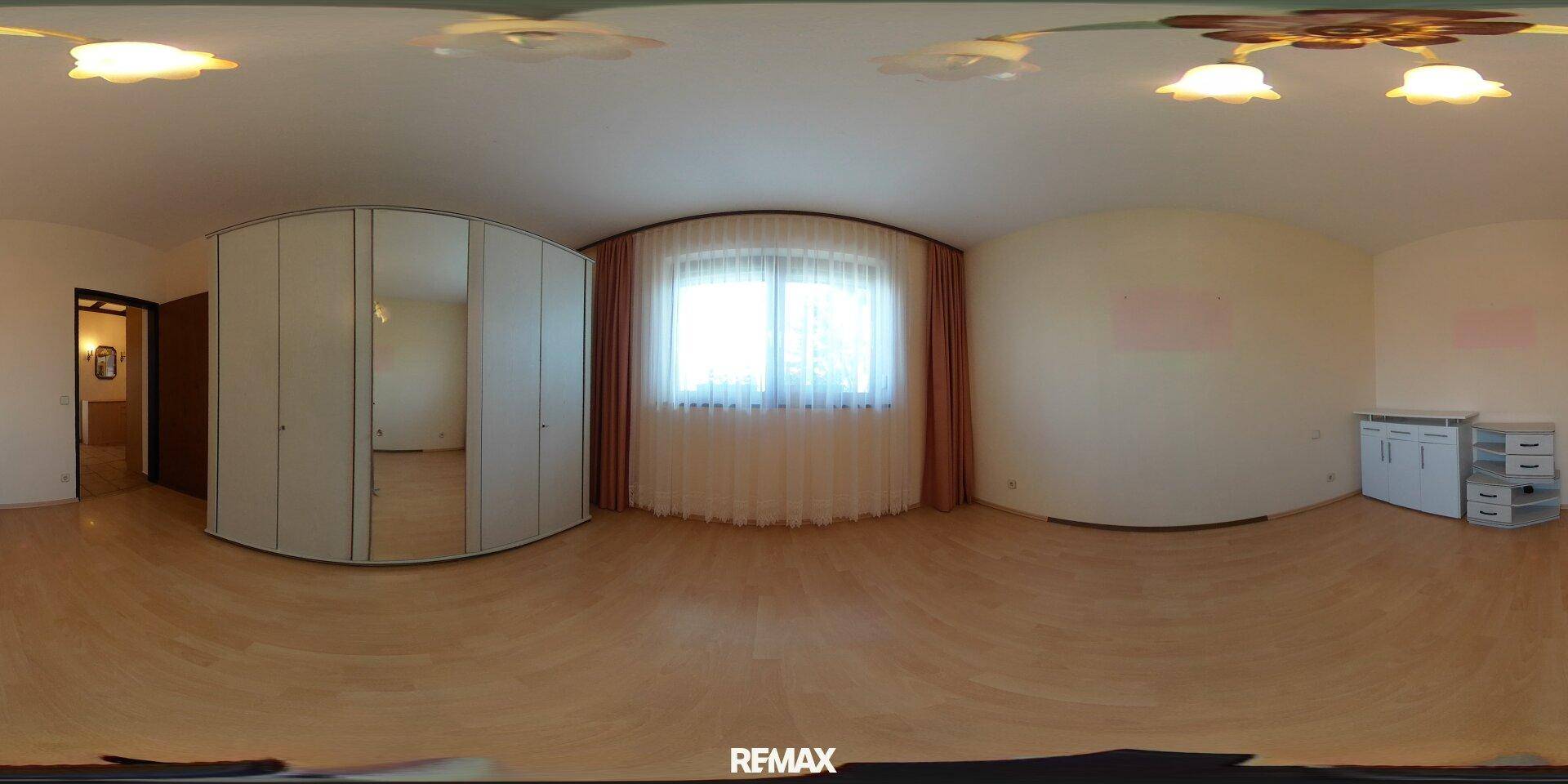 Helles Schlafzimmer mit hellem Holzboden, großem Spiegelschrank und Fenster mit Vorhängen.