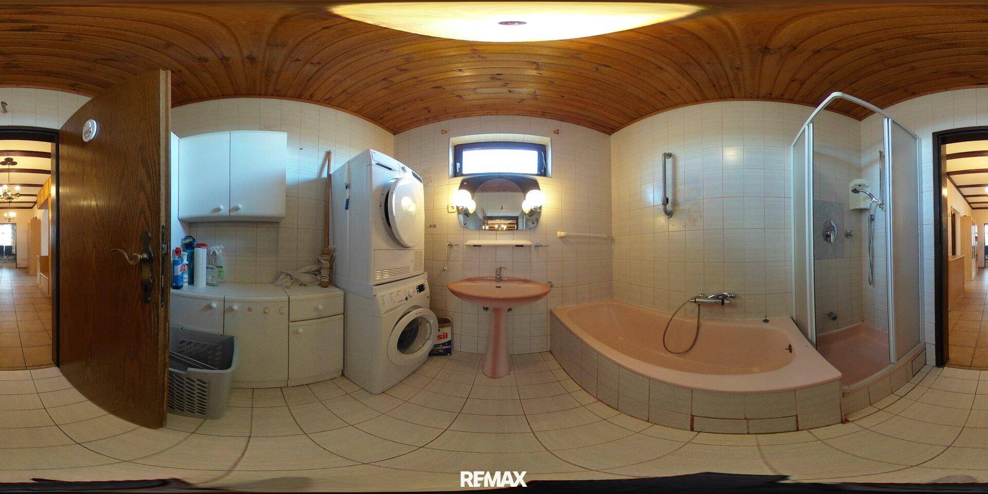 Badezimmer mit Waschmaschine, Trockner, Badewanne, Dusche und einer Holzdecke.