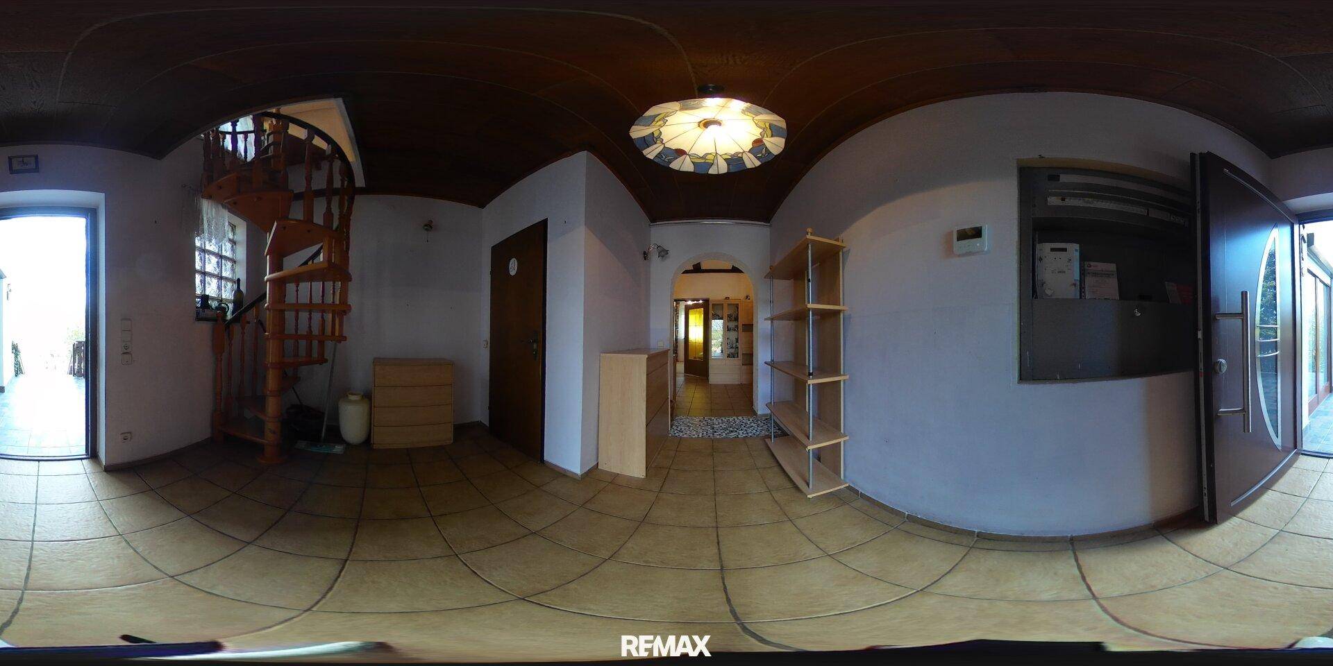 Flur mit einer eleganten Wendeltreppe, gefliestem Boden und einer Holzdecke.