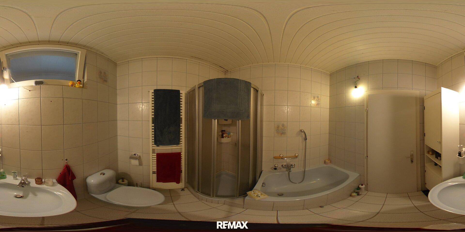 Gefliestes Badezimmer mit Dusche, Badewanne, WC, Doppelwaschbecken und Fenster.