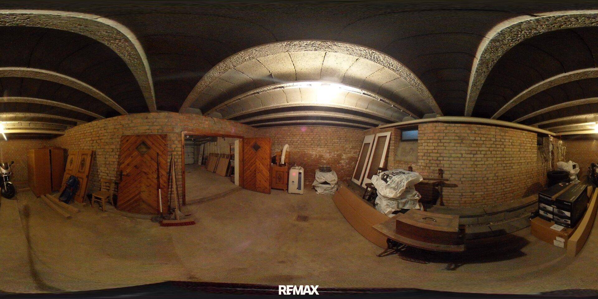Geräumiger Kellerraum mit unverputzten Ziegelwänden, Betonboden und gewölbter Decke, ideal als Lagerfläche.