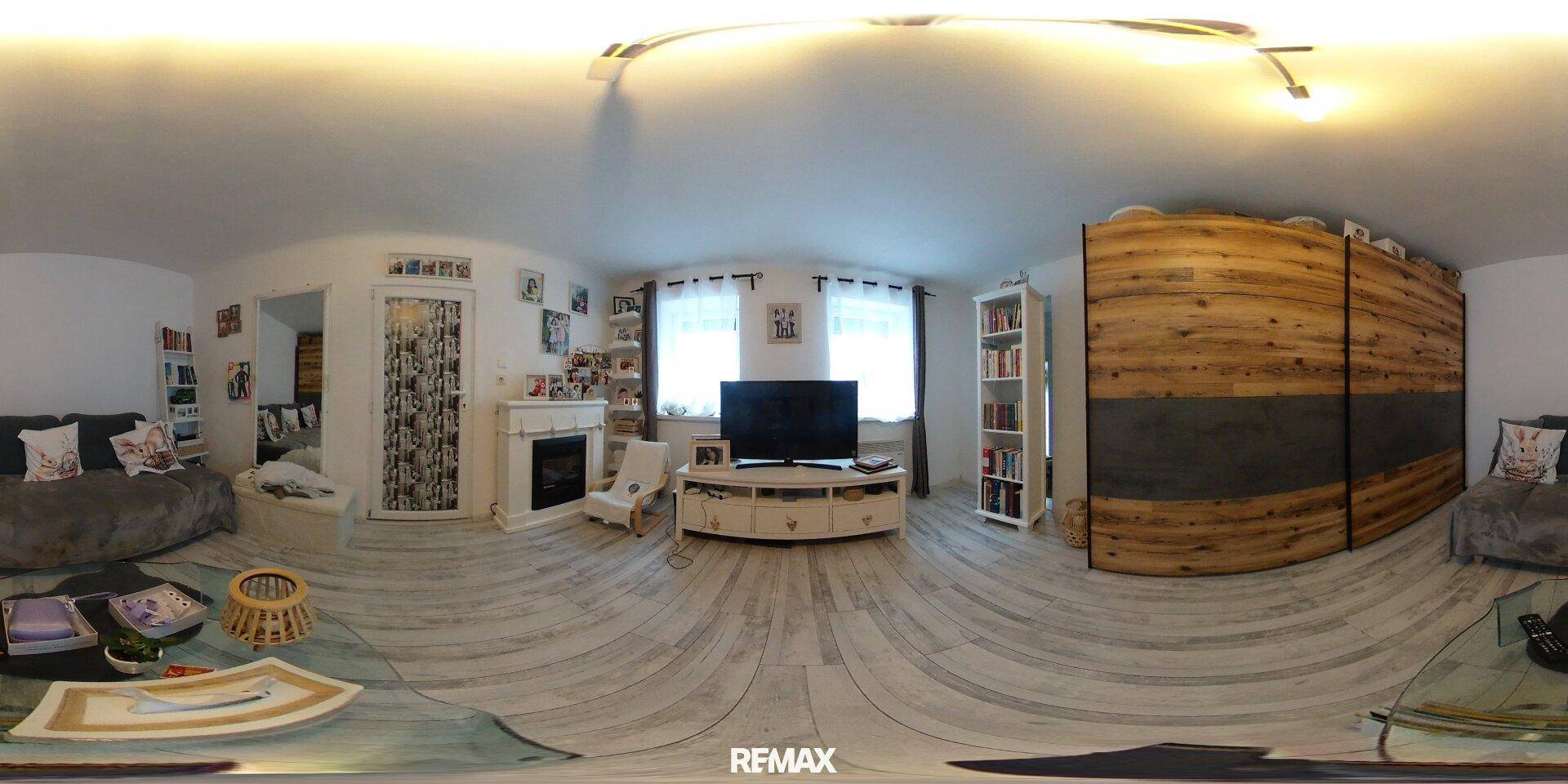 Panoramaansicht des hellen Wohnzimmers mit Holzboden, TV-Möbeln und einem großen Holzschrank.