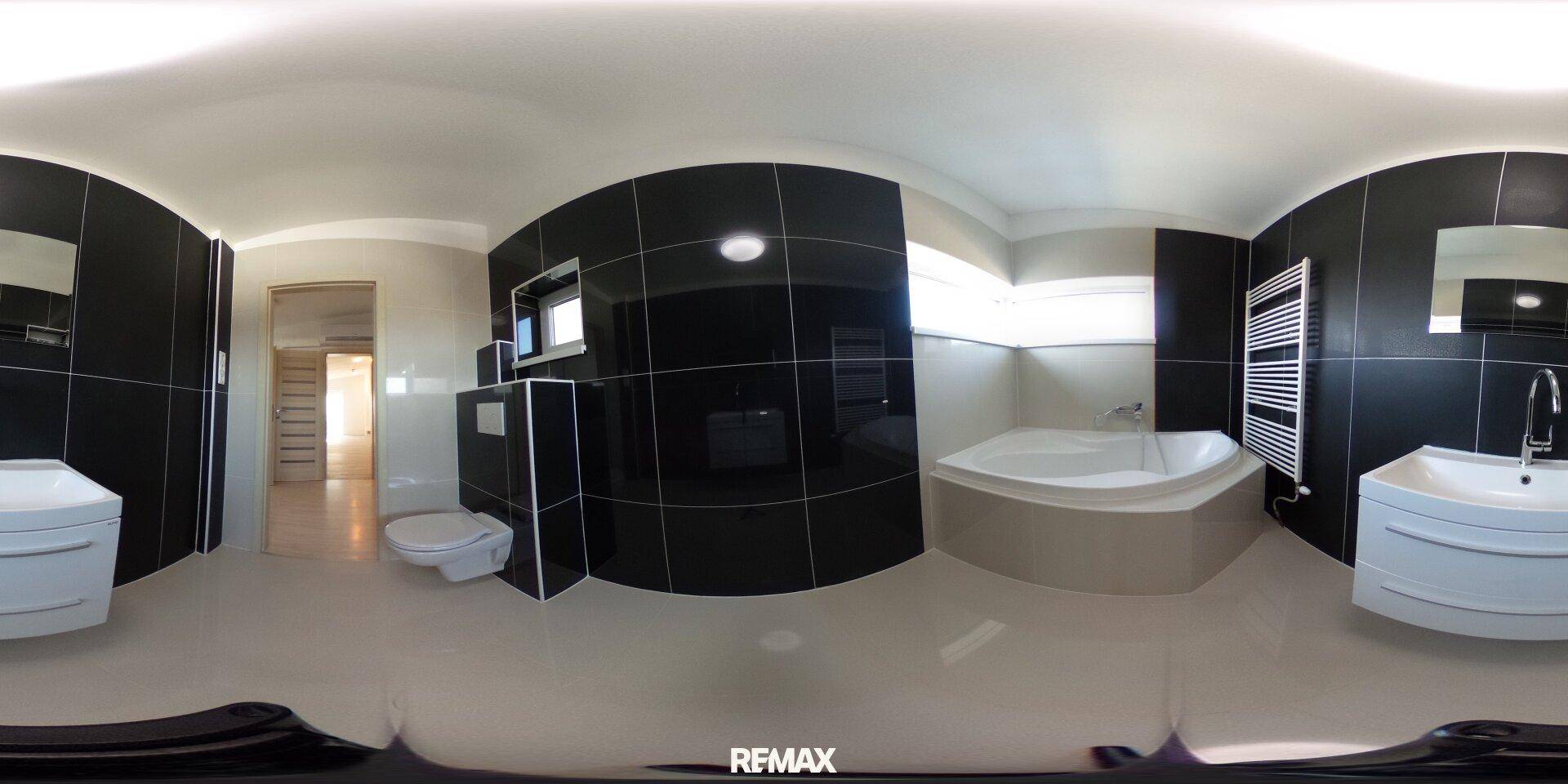 Geräumiges Badezimmer mit schwarzen und weißen Fliesen, Eckbadewanne und modernem Design.