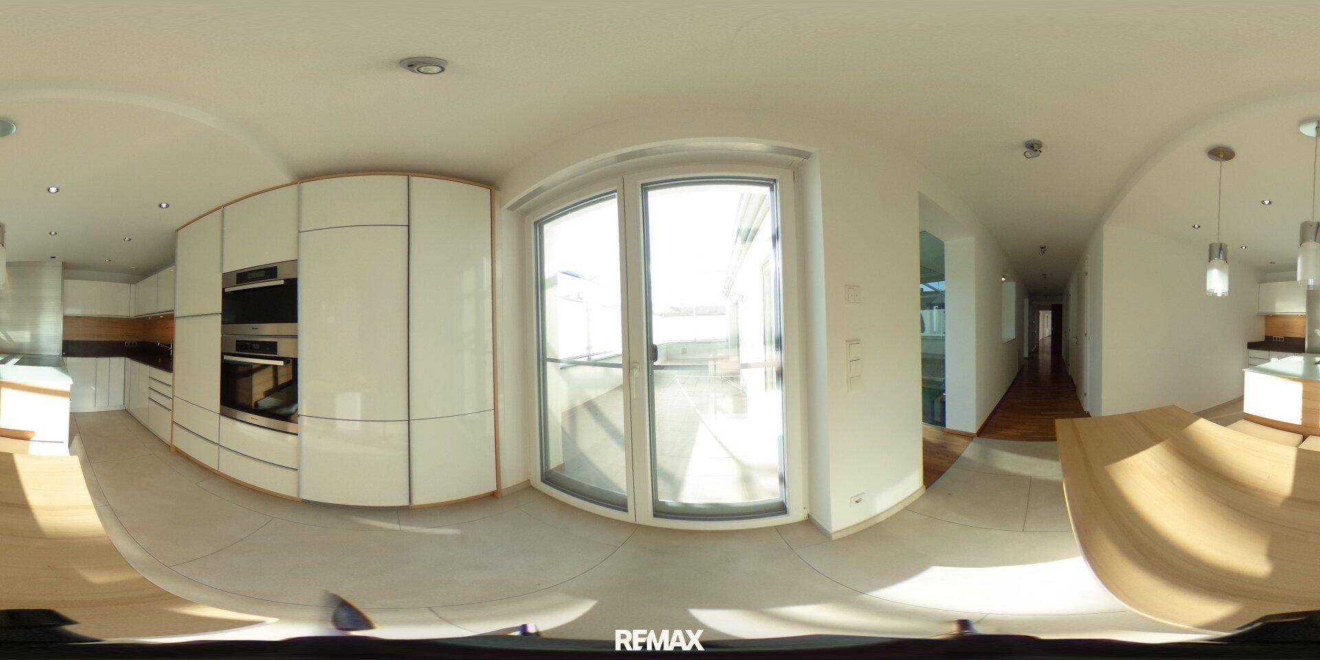 Panoramaaufnahme einer modernen Küche mit integrierten Geräten und Terrassenzugang.