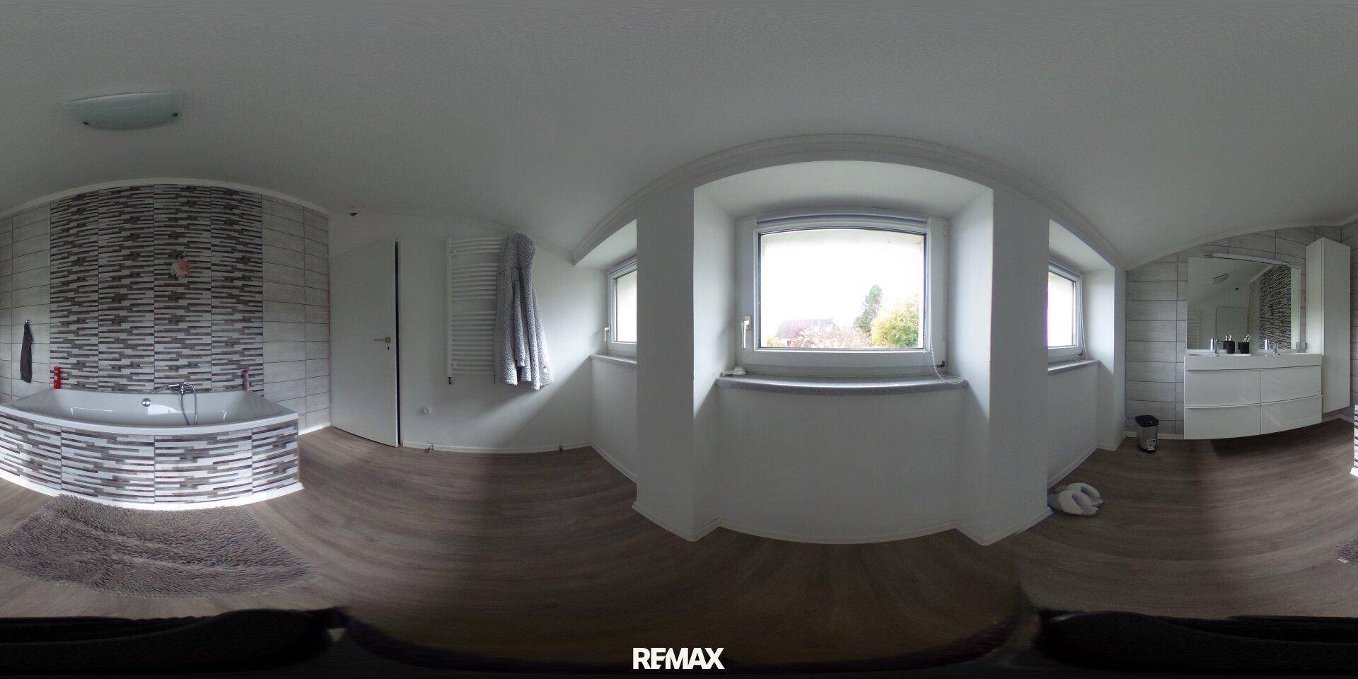 Geräumiges Badezimmer mit Badewanne, Doppelwaschtisch und großen Fenstern für viel Tageslicht.