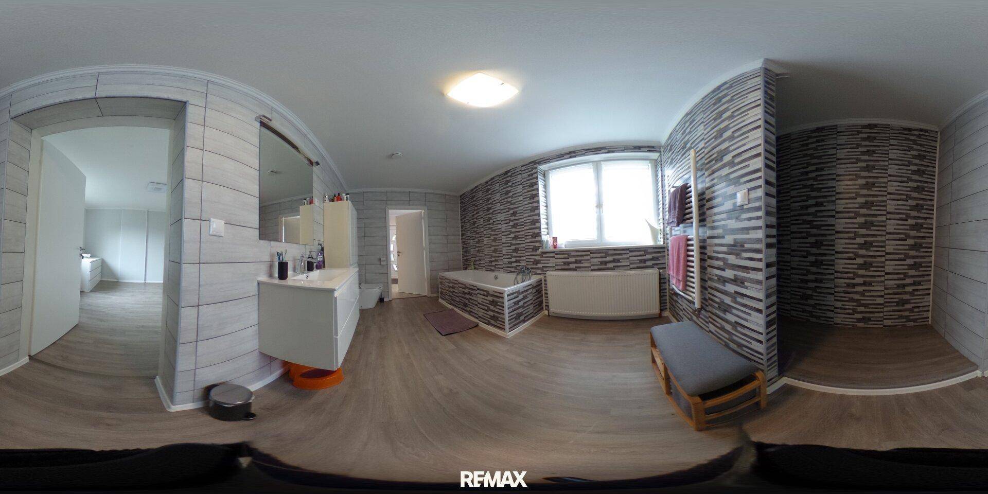 Modernes Badezimmer mit Badewanne, Duschbereich, Fenster und stilvollen Fliesen in Grau- und Weißtönen.