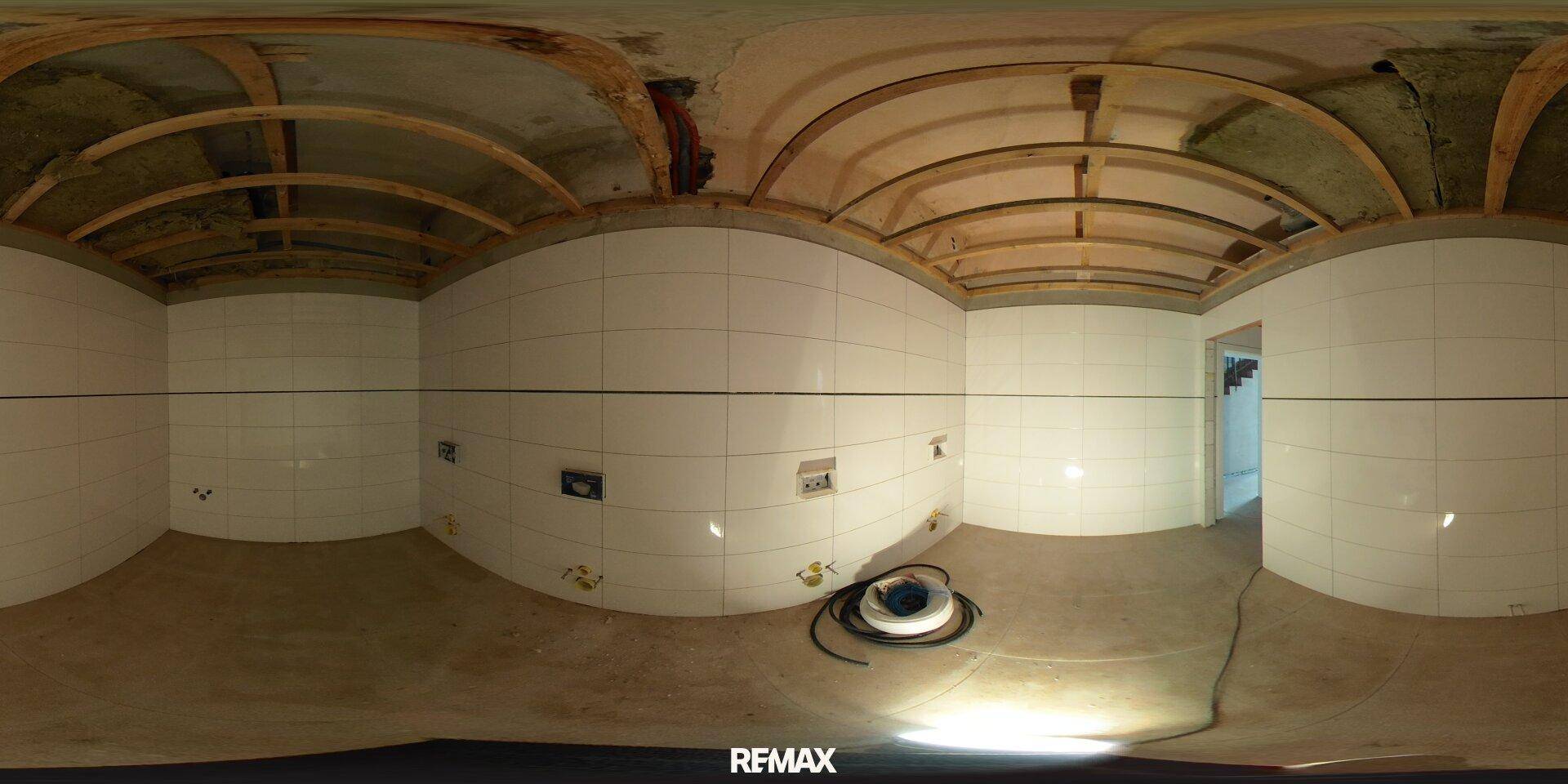 Badezimmer im Rohbau mit weißen Wandfliesen und sichtbarer Deckenkonstruktion, bereit für den Ausbau.