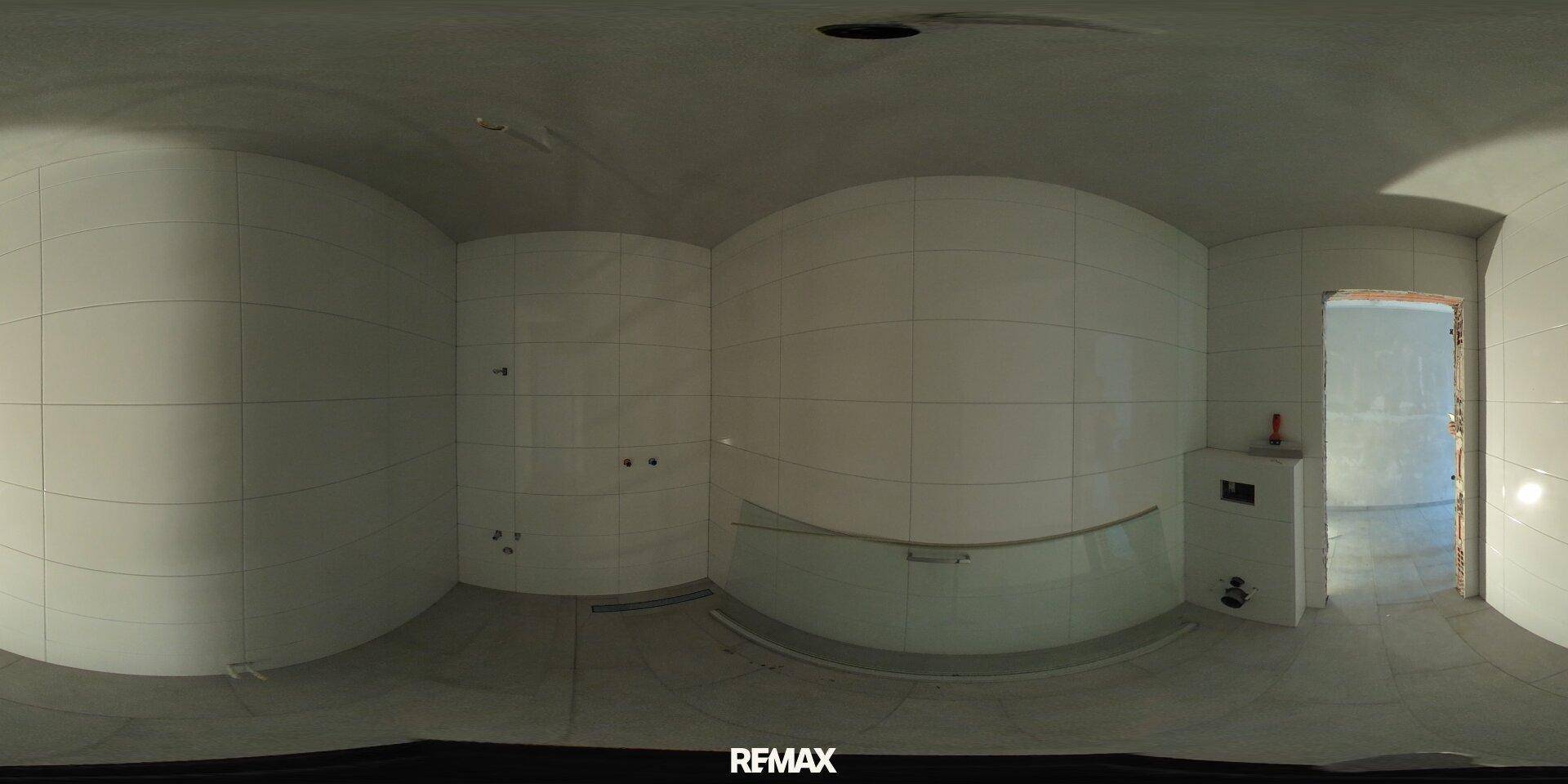 Badezimmer im Rohbau mit weißen Fliesenwänden und einer Duschkabine.