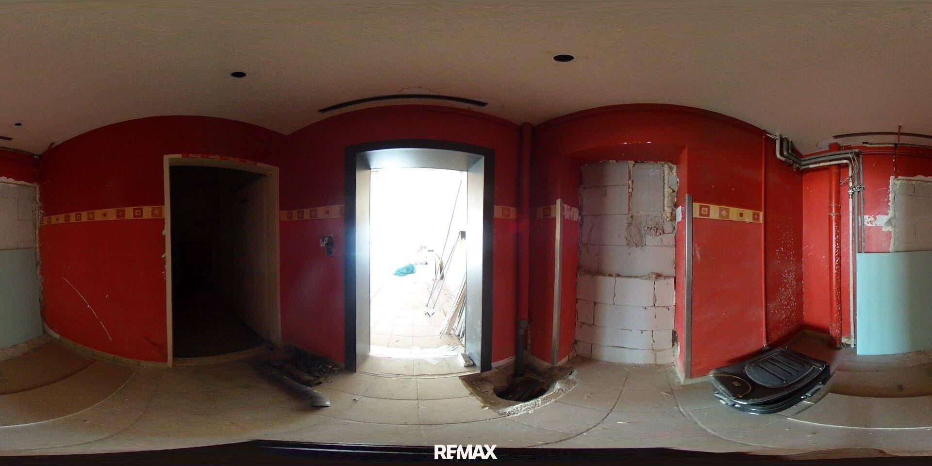 Raum im Umbau mit roten Wänden und sichtbaren Installationen, bereit für die Fertigstellung.