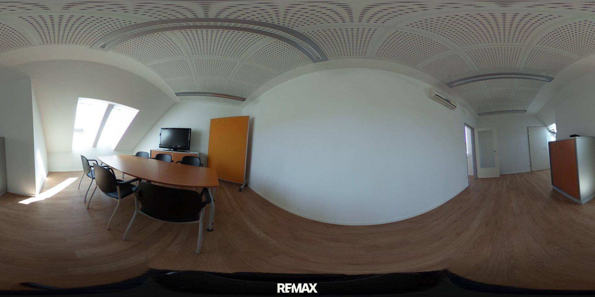 Panoramaansicht eines Büros im Dachgeschoss mit Holzboden, Dachschrägen und Besprechungstisch.