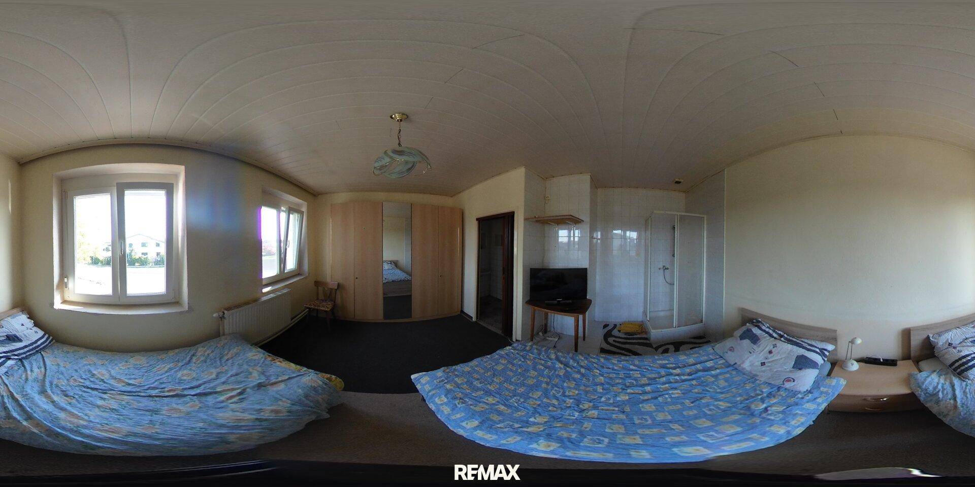 Geräumiges Schlafzimmer mit zwei Betten, Kleiderschrank und großen Fenstern für viel Licht.