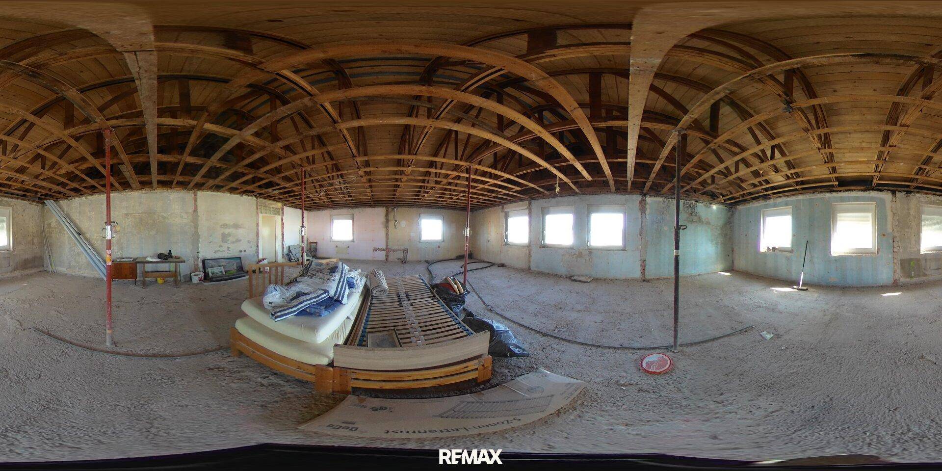 Großer Dachboden im Rohbau mit sichtbarer Holzkonstruktion und vielen Fenstern, bereit für den Ausbau.