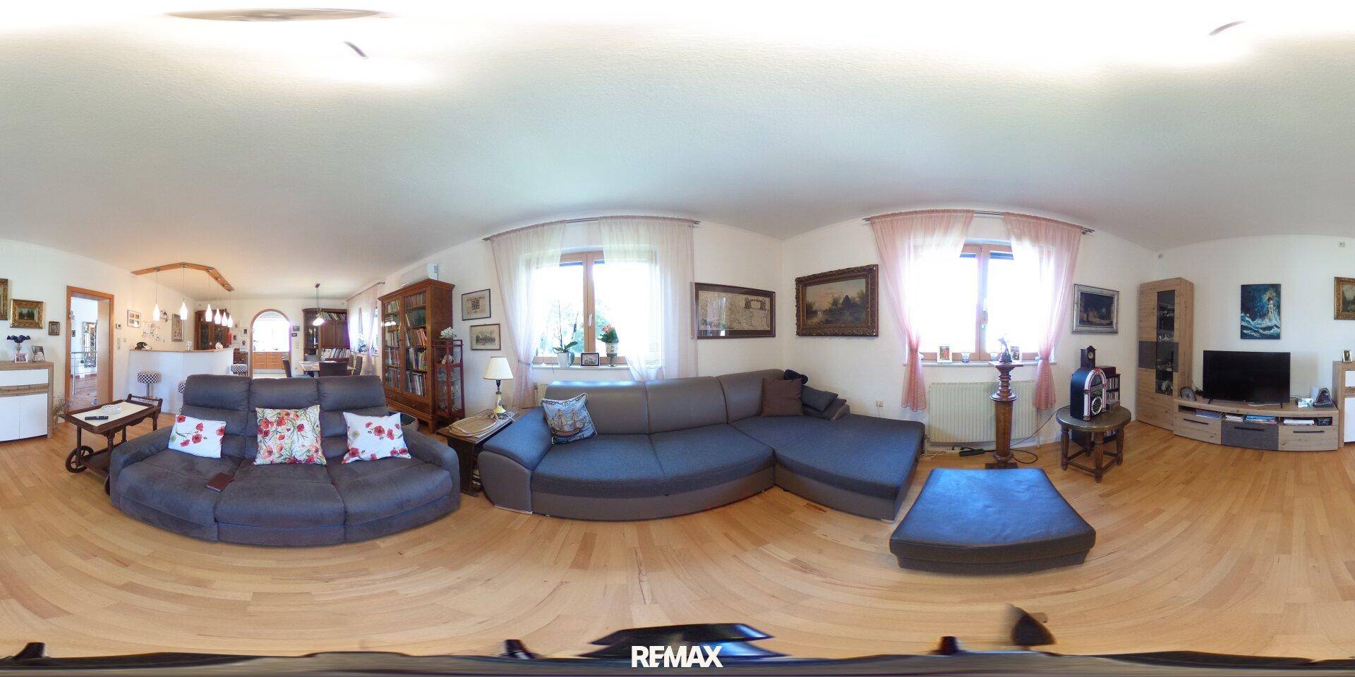Geräumiges Wohnzimmer mit Holzboden, bequemen Sofas und großen Fenstern für viel Licht.