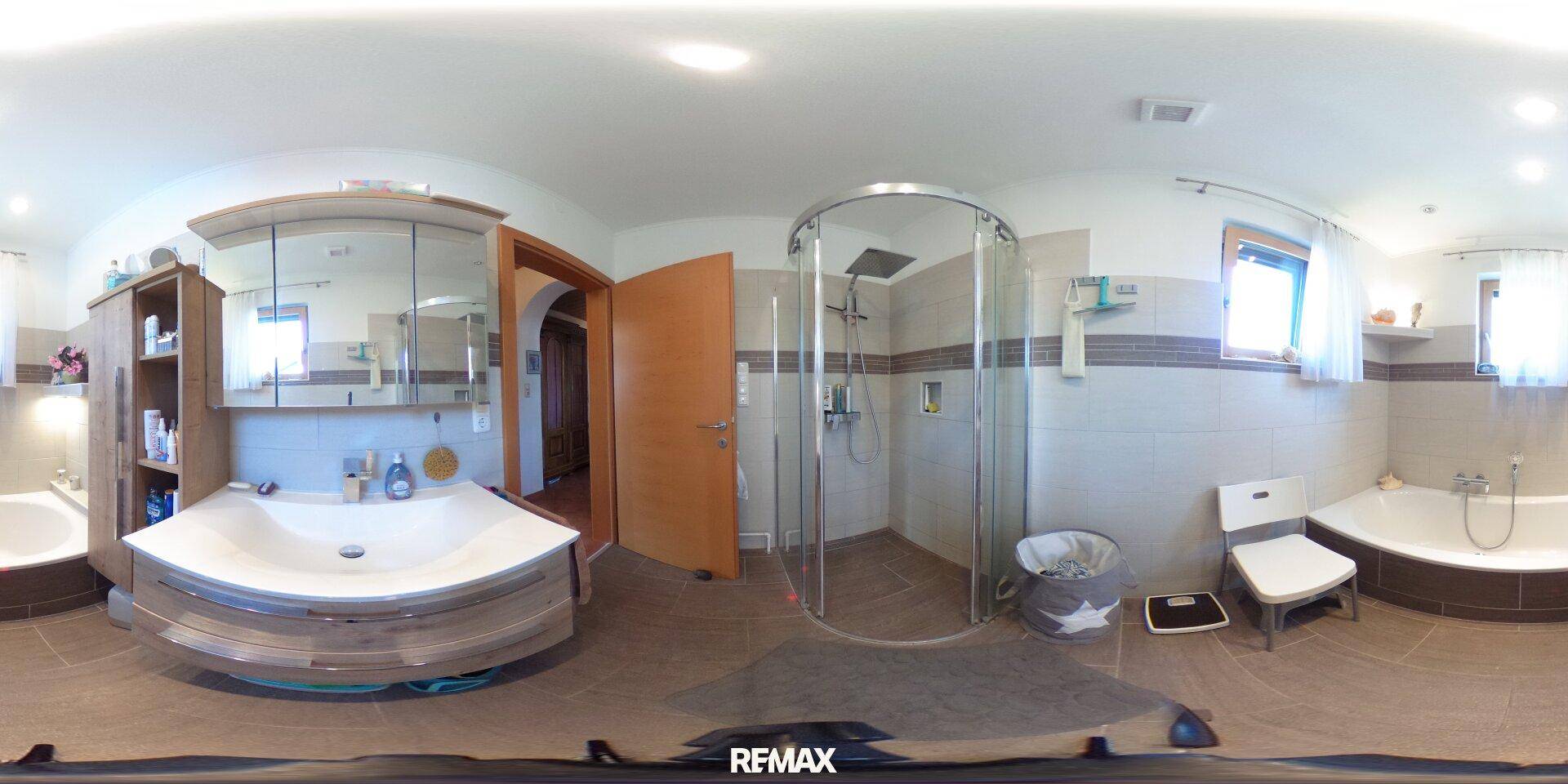 Badezimmer mit Dusche, Badewanne, Doppelwaschbecken und hellen Fliesen.