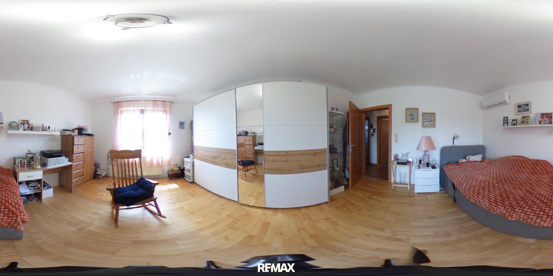 Helles Schlafzimmer mit Holzboden, modernem Kleiderschrank und großem Fenster.