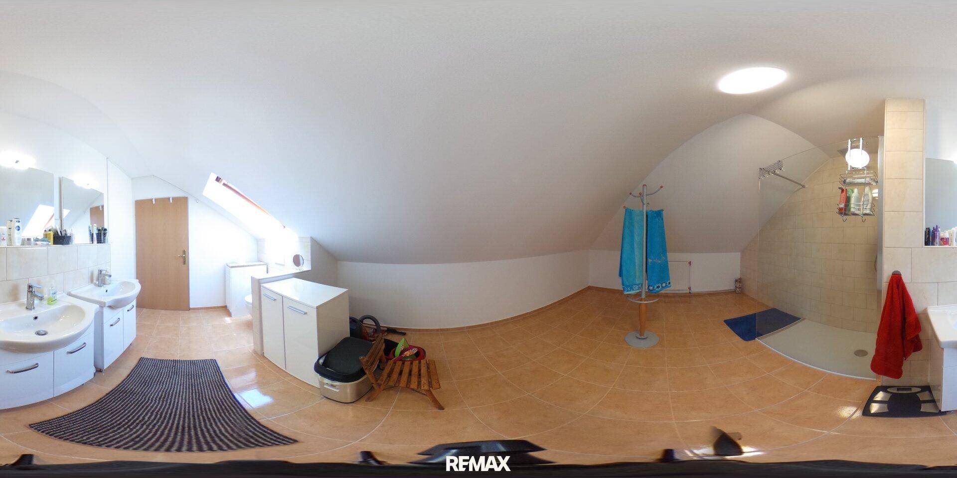 Badezimmer im Dachgeschoss mit Dusche, Doppelwaschbecken, Dachfenster und Fliesenboden.