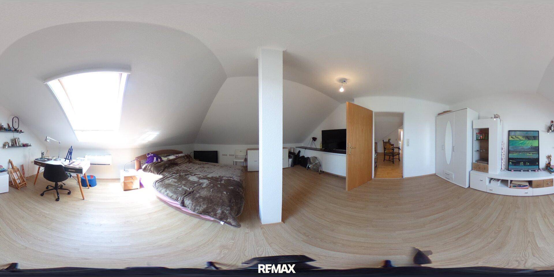 Helles Schlafzimmer im Dachgeschoss mit Holzboden, Dachfenster und Schreibtisch.