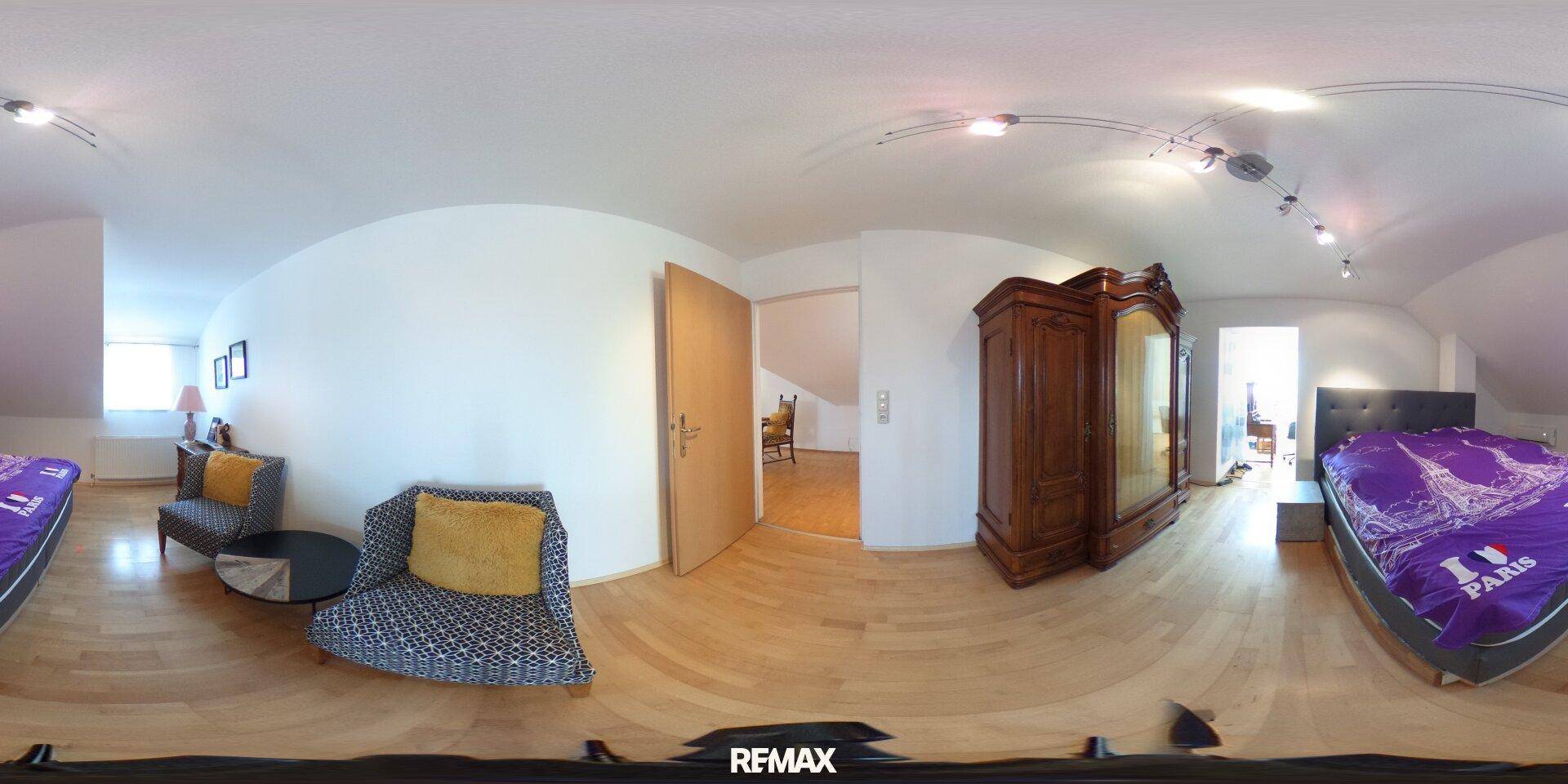 Schlafzimmer im Dachgeschoss mit Holzboden, klassischem Holzschrank und Dachschrägen.