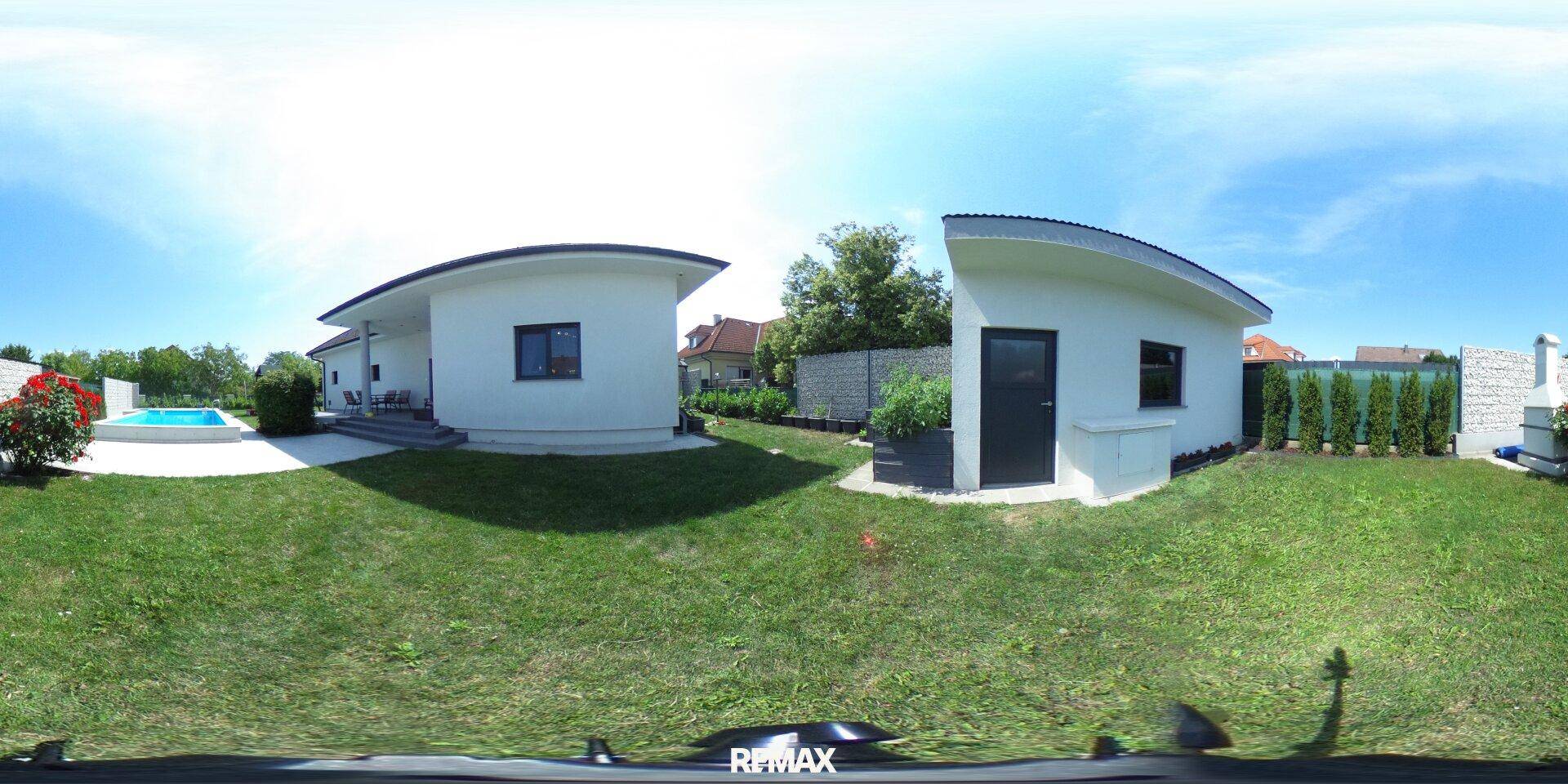 Gepflegter Gartenbereich mit Rasen, Bäumen und Blick auf das Haus und den Pool.