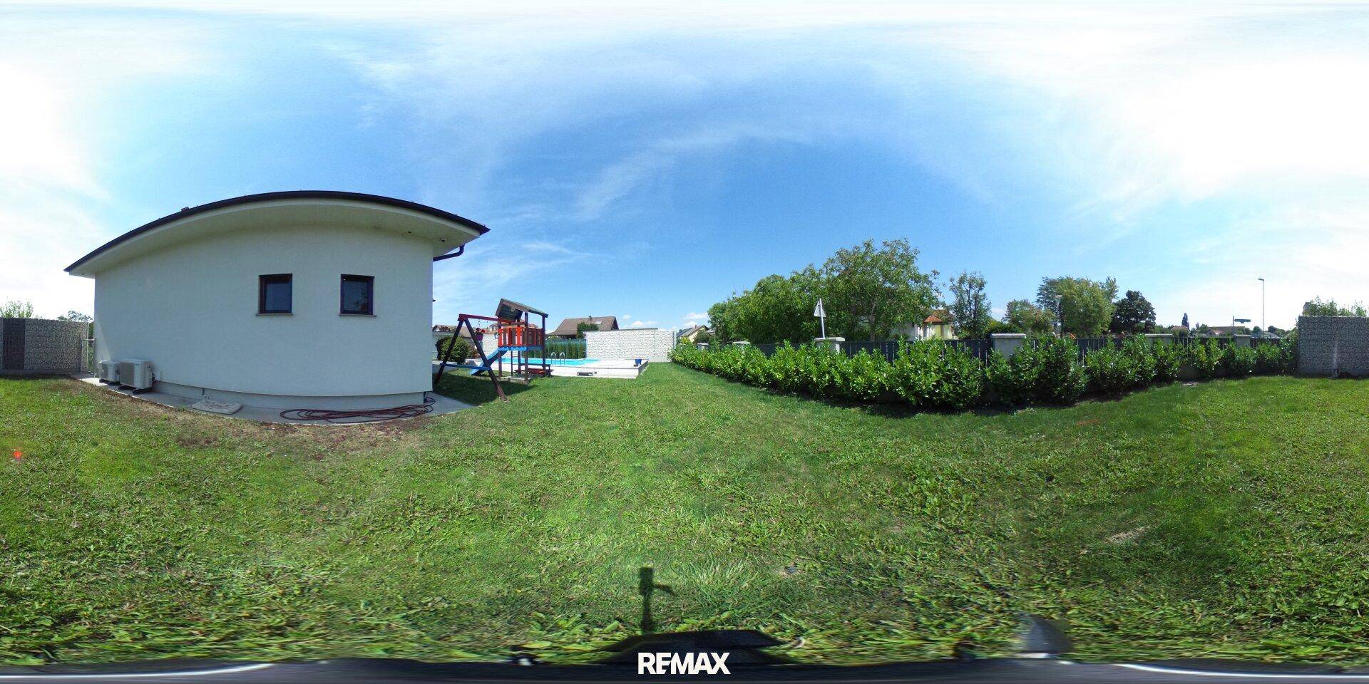 Großer Gartenbereich hinter dem Haus mit Rasenfläche und Spielgeräten.