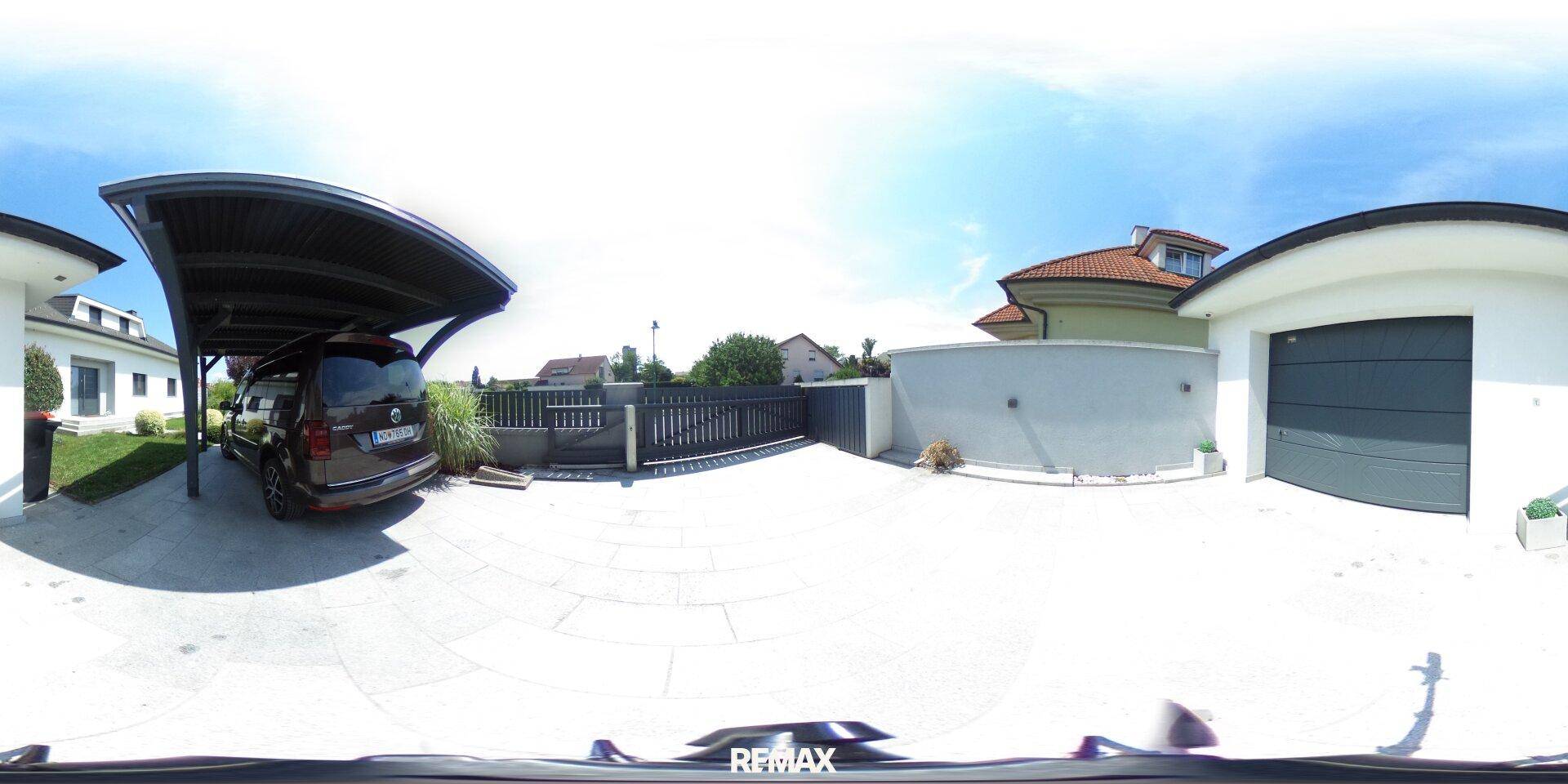 Außenbereich mit Carport, Garage und gepflasterter Einfahrt.